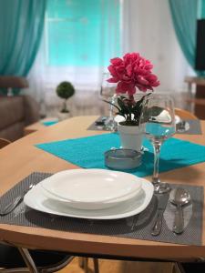 einen Tisch mit einer weißen Platte und einer Blumenvase in der Unterkunft BellaVista Apartmani in Stara Pazova