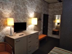 a bedroom with a dresser with a television and a mirror at Guesthouse Na Volge in Rybinsk