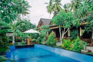 a villa with a swimming pool in front of a house at Mertasari Bungalows in Nusa Penida