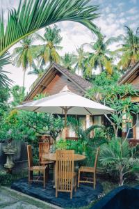 a wooden table with chairs and an umbrella at Mertasari Bungalows in Nusa Penida