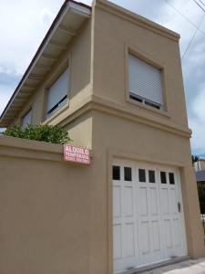 a house with a garage door and a sign on it at Departamento Necochea in Necochea