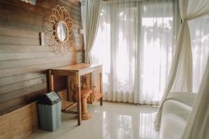 - une chambre avec une table, une fenêtre et une poubelle dans l'établissement Mertasari Bungalows, à Nusa Penida