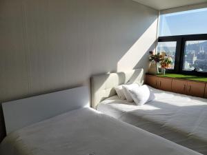 1 dormitorio con 2 camas blancas y ventana en Samseong Coexmall AA, en Seúl