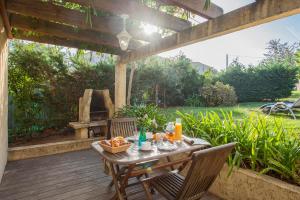 une table et des chaises sur une terrasse en bois avec une cheminée dans l'établissement minivilla lilas indépendante à Calvi avec jardin et piscine jardin et bbq, à Calvi
