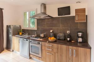 a kitchen with a sink and a stove top oven at minivilla lilas indépendante à Calvi avec jardin et piscine jardin et bbq in Calvi