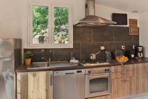 uma cozinha com um lavatório e um fogão forno superior em minivilla lilas indépendante à Calvi avec jardin et piscine jardin et bbq em Calvi