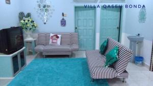 a living room with two chairs and a television at Villa Qaseh Bonda in Kuala Terengganu