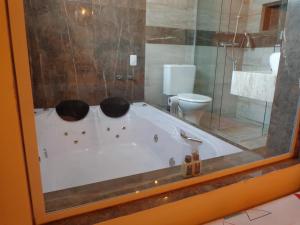 uma banheira na casa de banho com WC em Monte Verde Inn Suítes com Hidromassagem dupla em Monte Verde