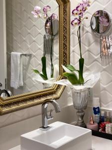 um lavatório de casa de banho com um espelho e um vaso de flores em Charme Comforto Beira Mar em Angra dos Reis