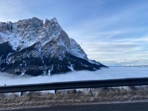 a mountain above a layer of fog next to a road at Appartamento Alpe di Siusi in Alpe di Siusi