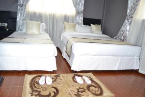 two beds with slippers on the floor in a room at Panone Hotels - King'ori Kilimanjaro Airport in Moshi