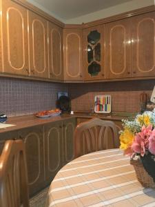 a kitchen with wooden cabinets and a table with flowers at Armand's home in Korçë