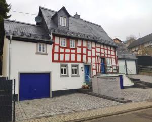 una casa roja y blanca con un garaje azul en Hübingen Cottage, en Hübingen