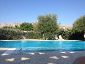 a blue swimming pool with two chairs and trees at Deliziosa Villa a 500 metri dal mare con Piscina in Terrasini