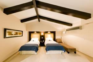 two beds in a hotel room with a ceiling at The Beach House in Panama City