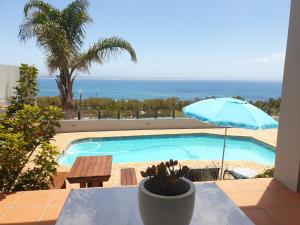 a table with a blue umbrella and a swimming pool at 59 LongSantos in Mossel Bay