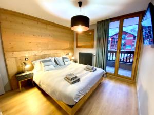 1 dormitorio con cama grande y ventana grande en L'Écrin Alpin - somptueux 4 pièces NEUF cœur station en Les Deux Alpes