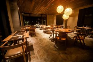 un restaurante con mesas de madera, sillas y luces en Makena Hotel en Icaraí