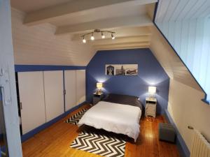 um quarto com uma cama com uma parede azul em Gîte bord de mer em Santec