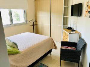 una camera con letto, sedia e televisore di Apartamento Acapulco Roosevelt a Punta del Este Altre 49 foto