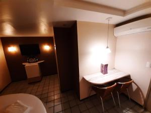 Fada Hotel - Motel Adults Only في ريسيفي: غرفة فندقية بطاولة وكراسي وتلفزيون
