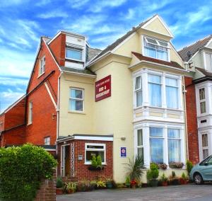 a house with a sign on the front of it at Harlequin Guest House with parking in Weymouth