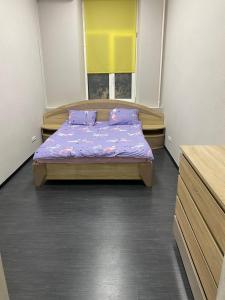 Schlafzimmer mit einem Bett mit lila Bettwäsche und Kissen in der Unterkunft Хостел Мажор in Kharkov