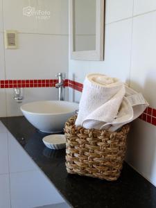 ein Badezimmer mit einem Korb mit Handtüchern und einem Waschbecken in der Unterkunft Dejeps in Punta Del Diablo
