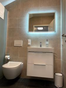 a bathroom with a toilet and a sink and a mirror at Gästehaus Veenstra in Kelberg