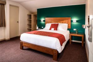 a bedroom with a large bed with a green wall at Maytaq Wasin Boutique Hotel in Cusco