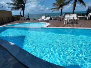 une grande piscine bleue à côté de l'océan dans l'établissement Atlântico flat 214, à Natal