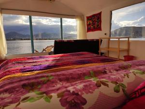 a bedroom with a bed with a floral bedspread and a window at Uros Quechua`s Lodge Titicaca in Puno +13 photos