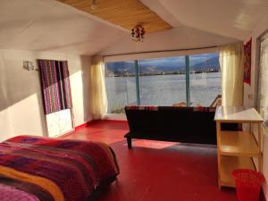 a bedroom with a bed and a tub and a large window at Uros Quechua`s Lodge Titicaca in Puno