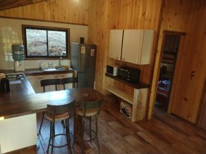 cocina con mesa y nevera en Cabaña El Mirador de Vichuquén, en Vichuquén