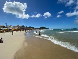 un grupo de personas en una playa con el océano en Hostel APÊ DO CRIS en Florianópolis