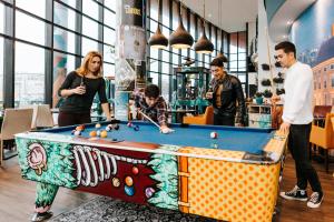 een groep mensen die rond een pooltafel staan bij The Hague Teleport Hotel in Den Haag