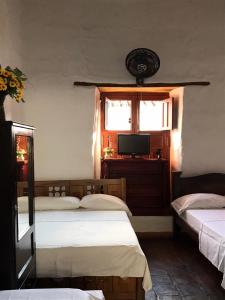 a bedroom with two beds and a tv and a window at Mi Casa en Barichara in Barichara