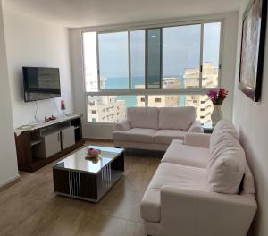 Una sala de estar con un sofá blanco y un televisor. en Kattyapartament 1103vista al mar, en Salinas