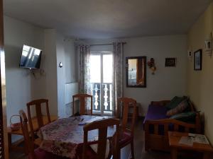 ein Wohnzimmer mit einem Tisch, Stühlen und einem Fenster in der Unterkunft MARBELLA FRENTE AL TELESILLA in Sierra Nevada