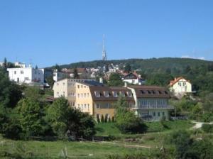 a large building on a hill with a town in the background at Pension Zlata Noha in Bratislava