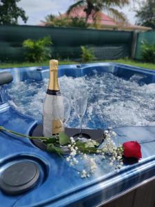 a bottle of champagne and a glass in a hot tub at BUNGALOW DE SAINT JACQUES in Saint-François
