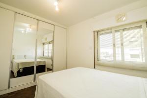 a white bedroom with a bed and a mirror at Apartamento aconchegante com estacionamento na 25 de março in Sao Paulo