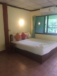 a bedroom with a bed with pillows and a window at Koh Ngai Resort in Ko Ngai