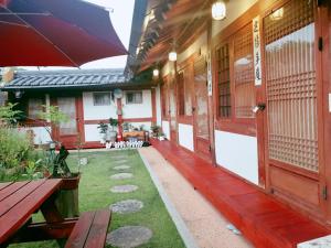 a porch of a house with a bench and an umbrella at Hanok Dream in Jeonju