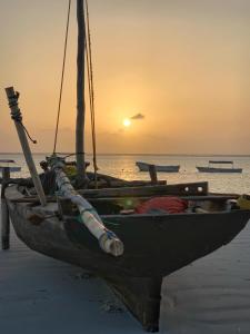 a boat sitting on the beach with the sunset in the background at Mohammed Bungalows and Restaurant in Matemwe