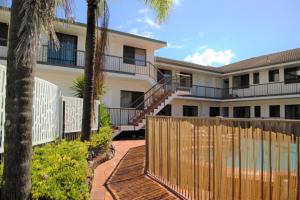 a building with a wooden fence and palm trees at Gold Coast Inn in Gold Coast