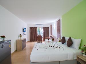 Un dormitorio con una gran cama blanca con rosas. en TJ Guesthouse, en Pattaya central