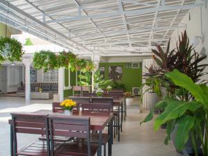 un restaurante con mesas de madera, sillas y plantas en TJ Guesthouse, en Pattaya central