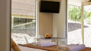 a room with a table and a television on a wall at One O One Cabins, Waiheke Island in Oneroa