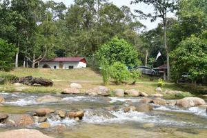 a river with rocks in front of a house at Lubok Jong Riverside, Sedim in Kulim
